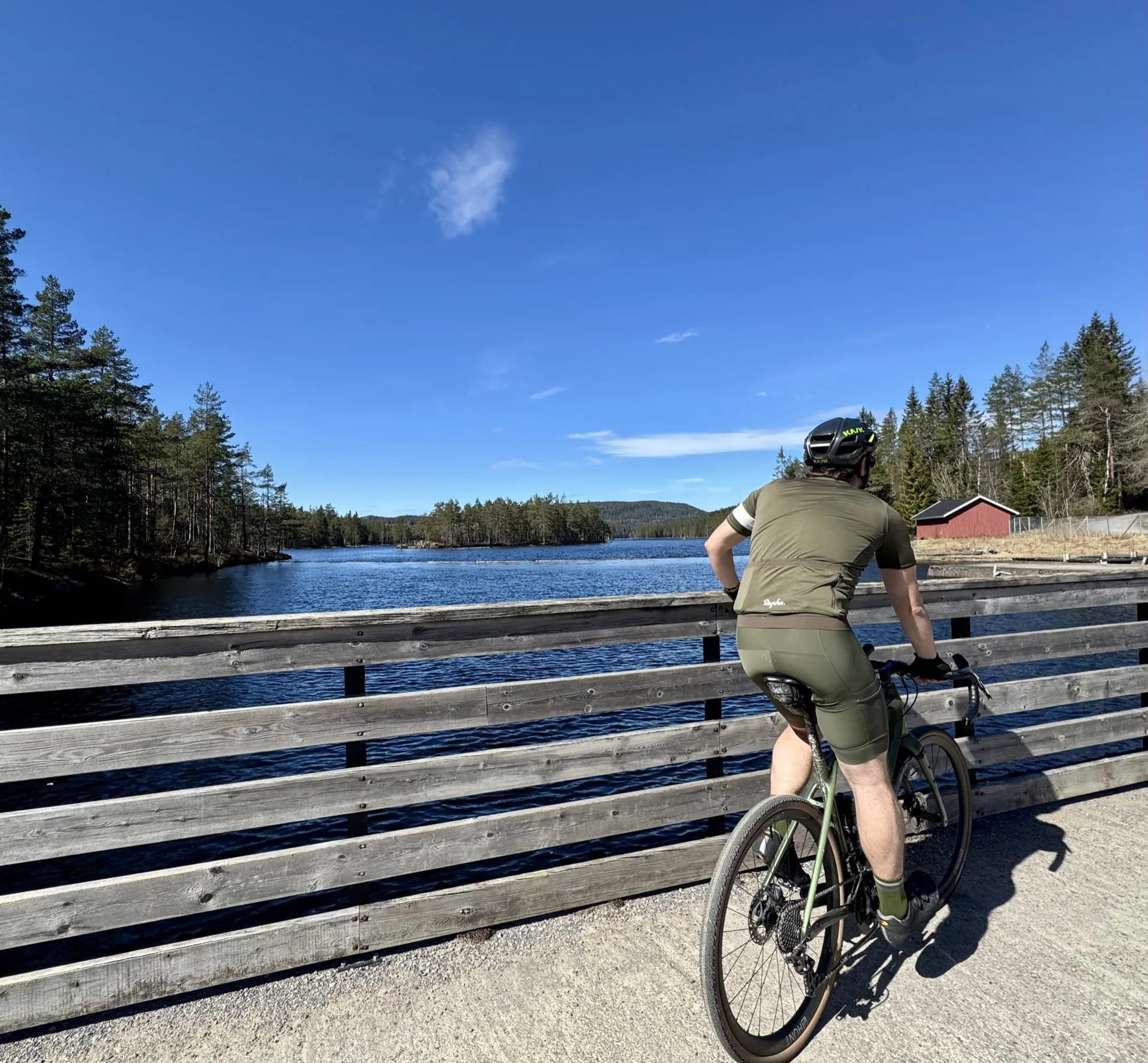 Cyclist on a bridge overlooking a Nordmarka forest lake
